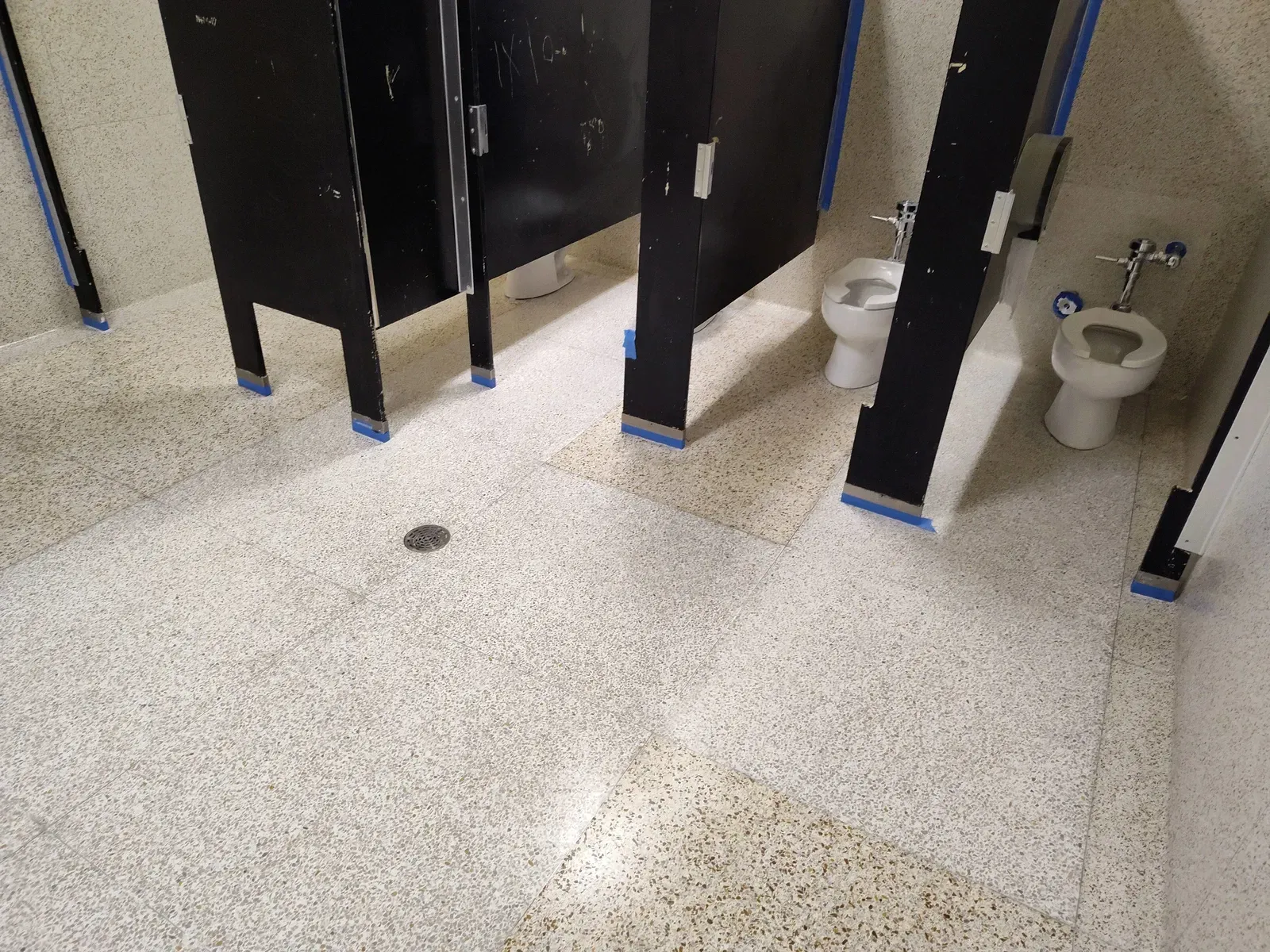 A bathroom with two toilets and two cubicles.