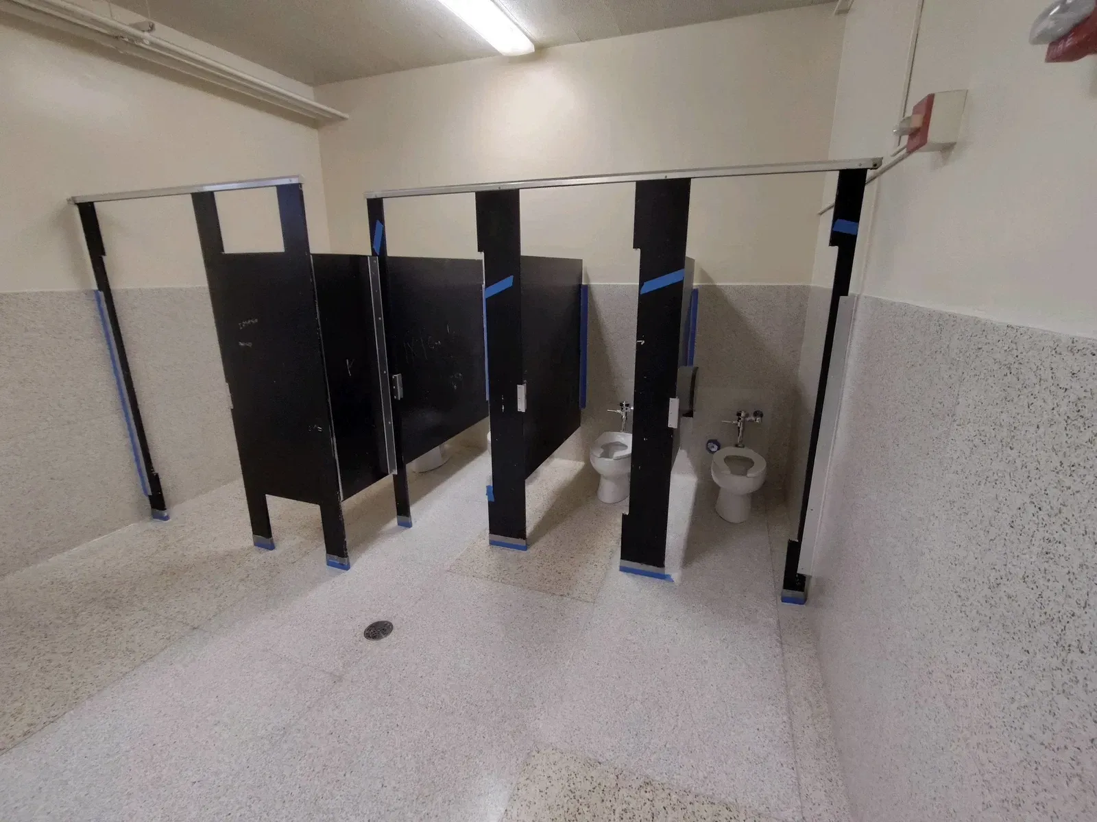 A bathroom with black stalls and two toilets