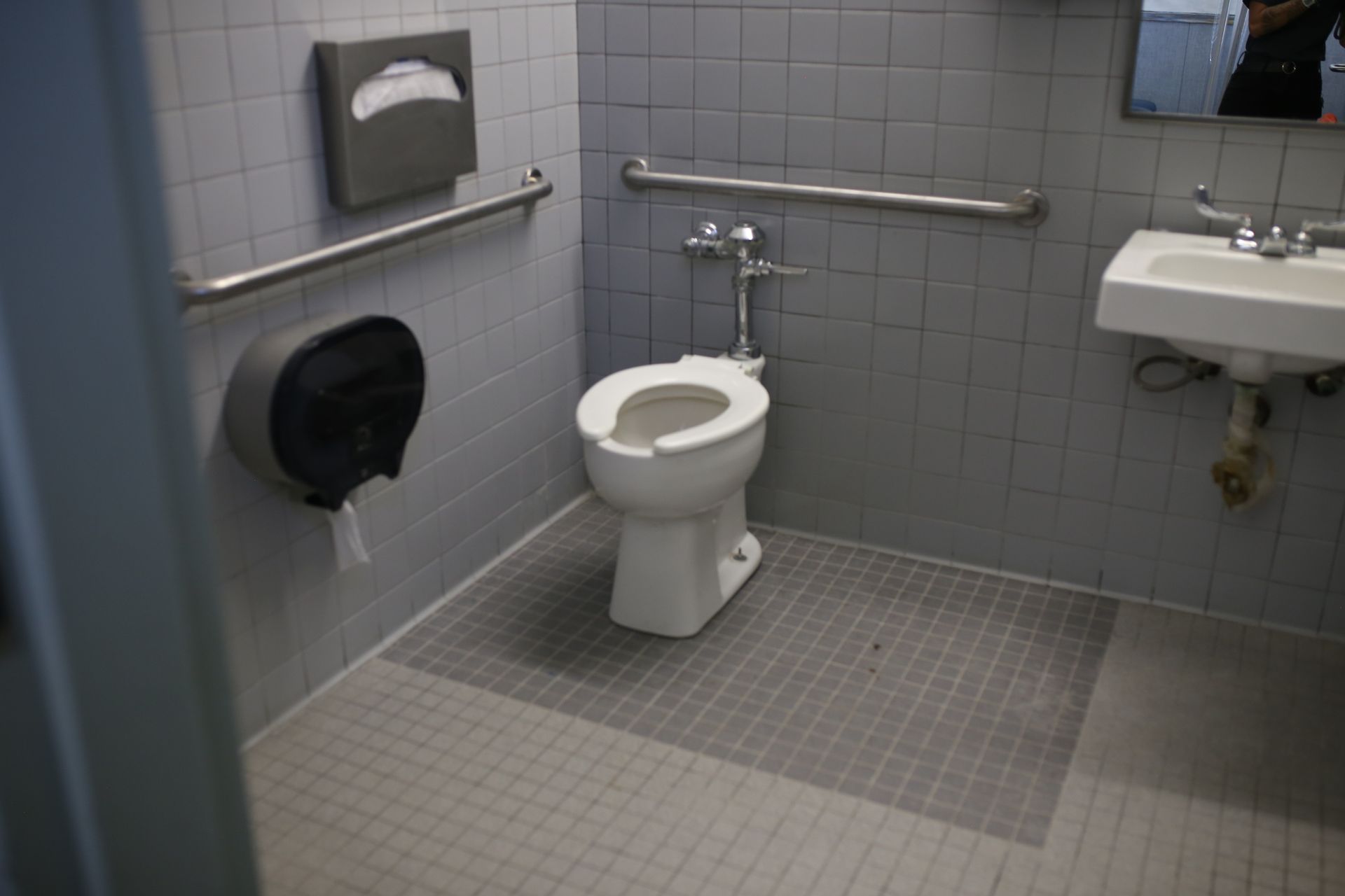 A bathroom with a toilet , sink and handrails