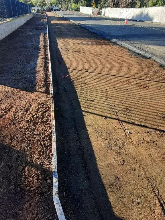 A dirt road with a drain in the middle of it.