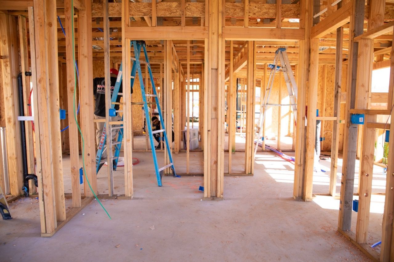 The inside of a house under construction with a blue ladder in the middle