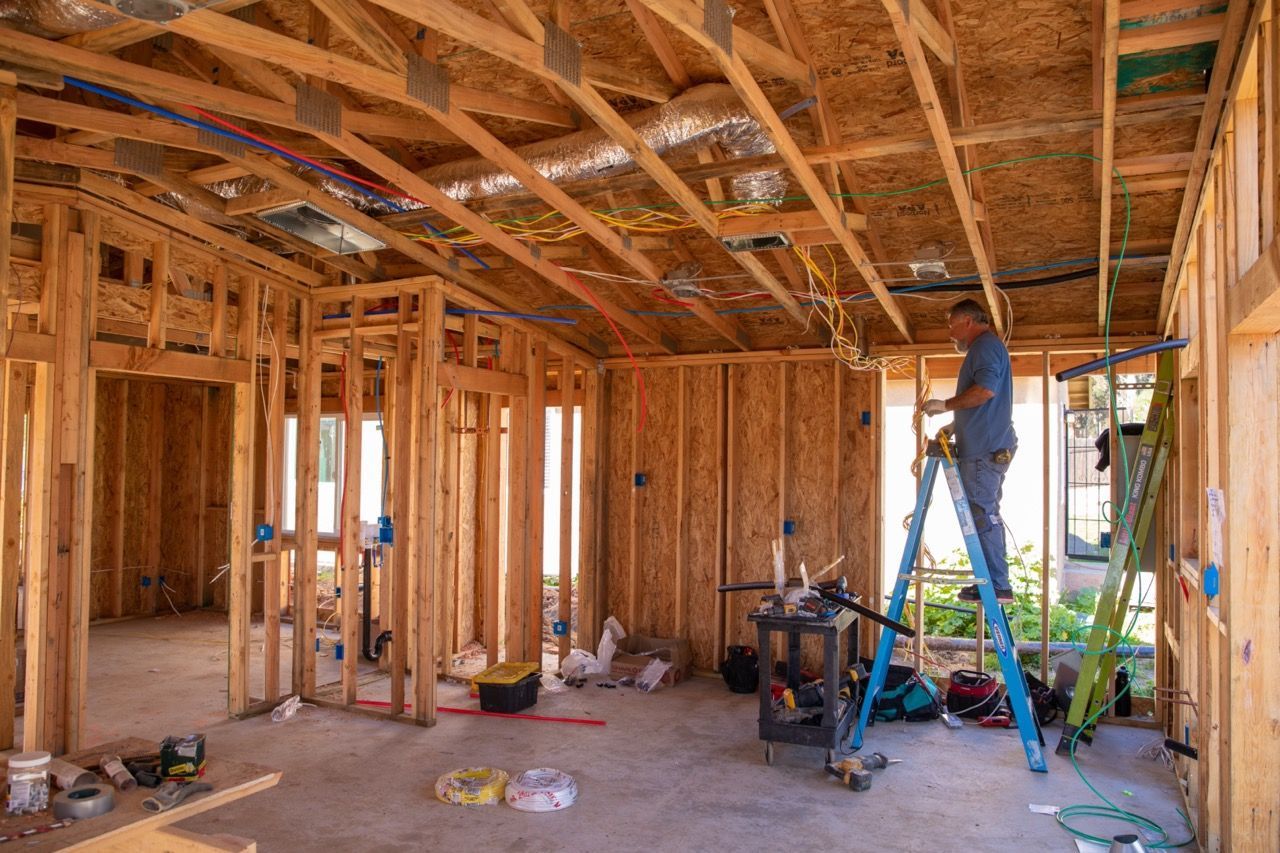 A man on a ladder is working on a house under construction