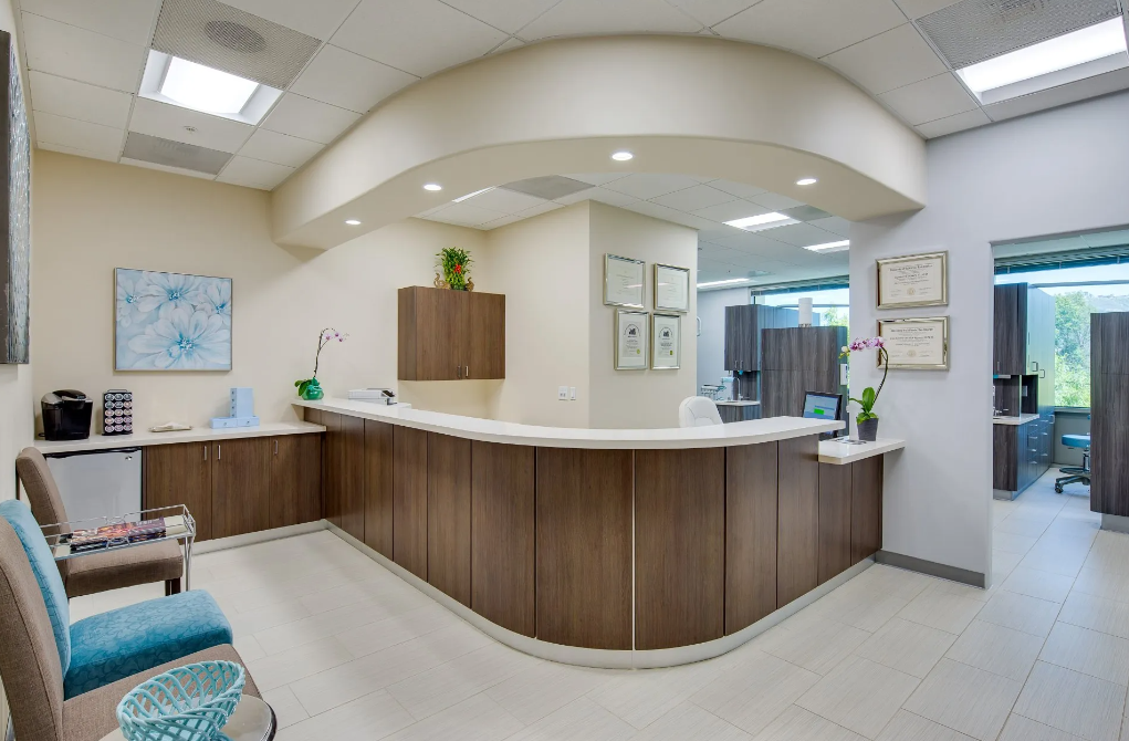 A panoramic view of a waiting room with a reception desk and chairs.