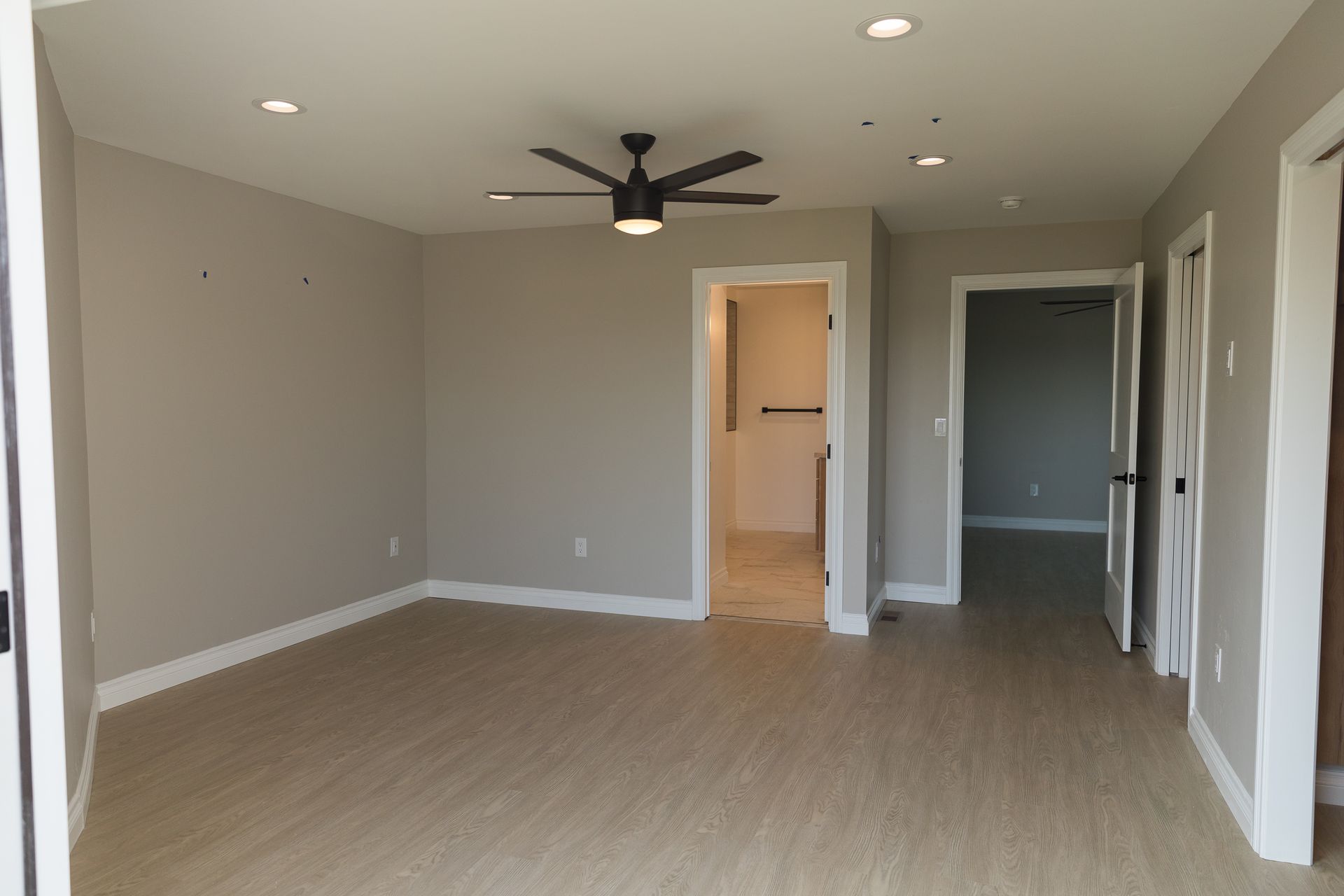 An empty living room with a ceiling fan and hardwood floors