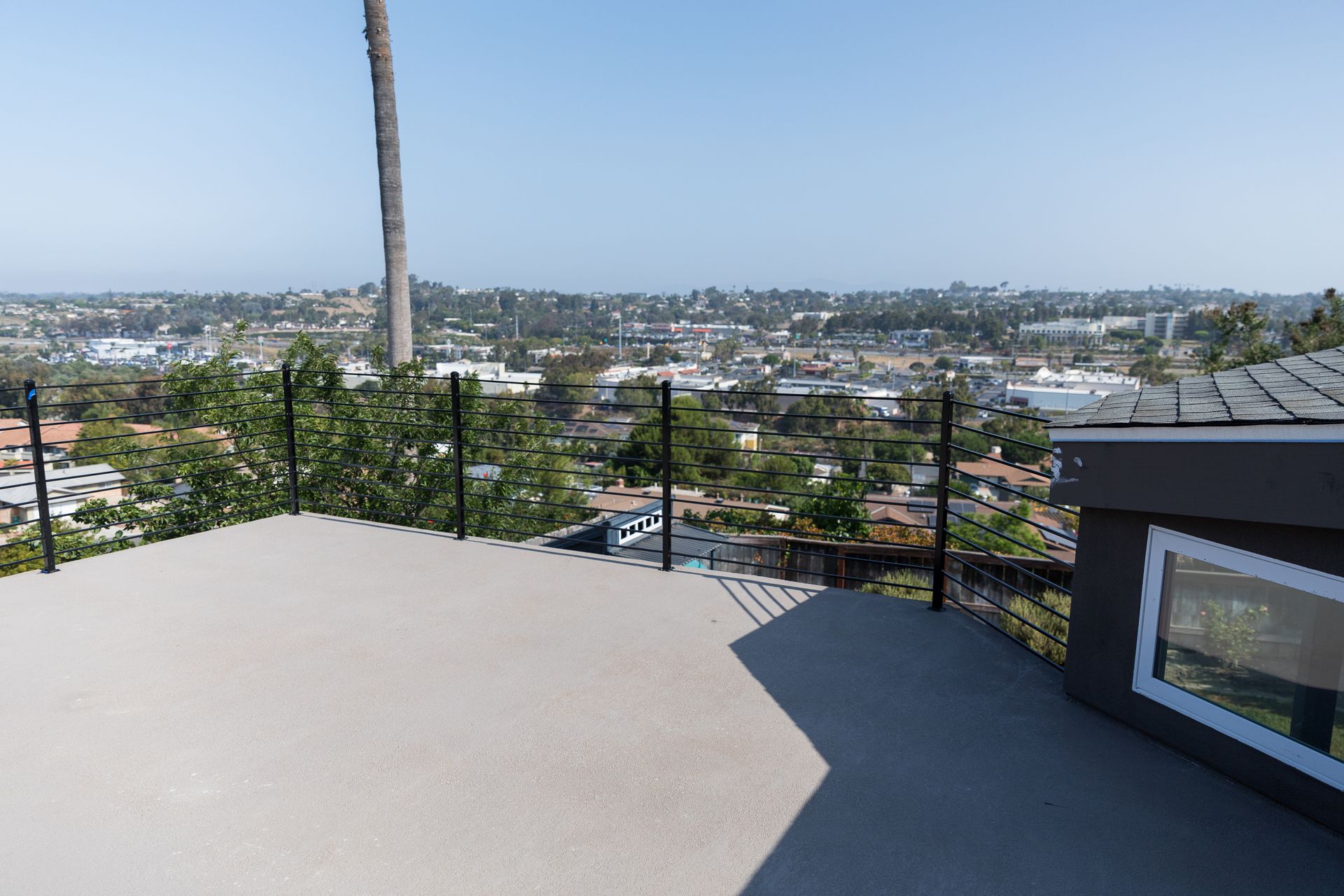 A balcony with a view of a city and a palm tree.