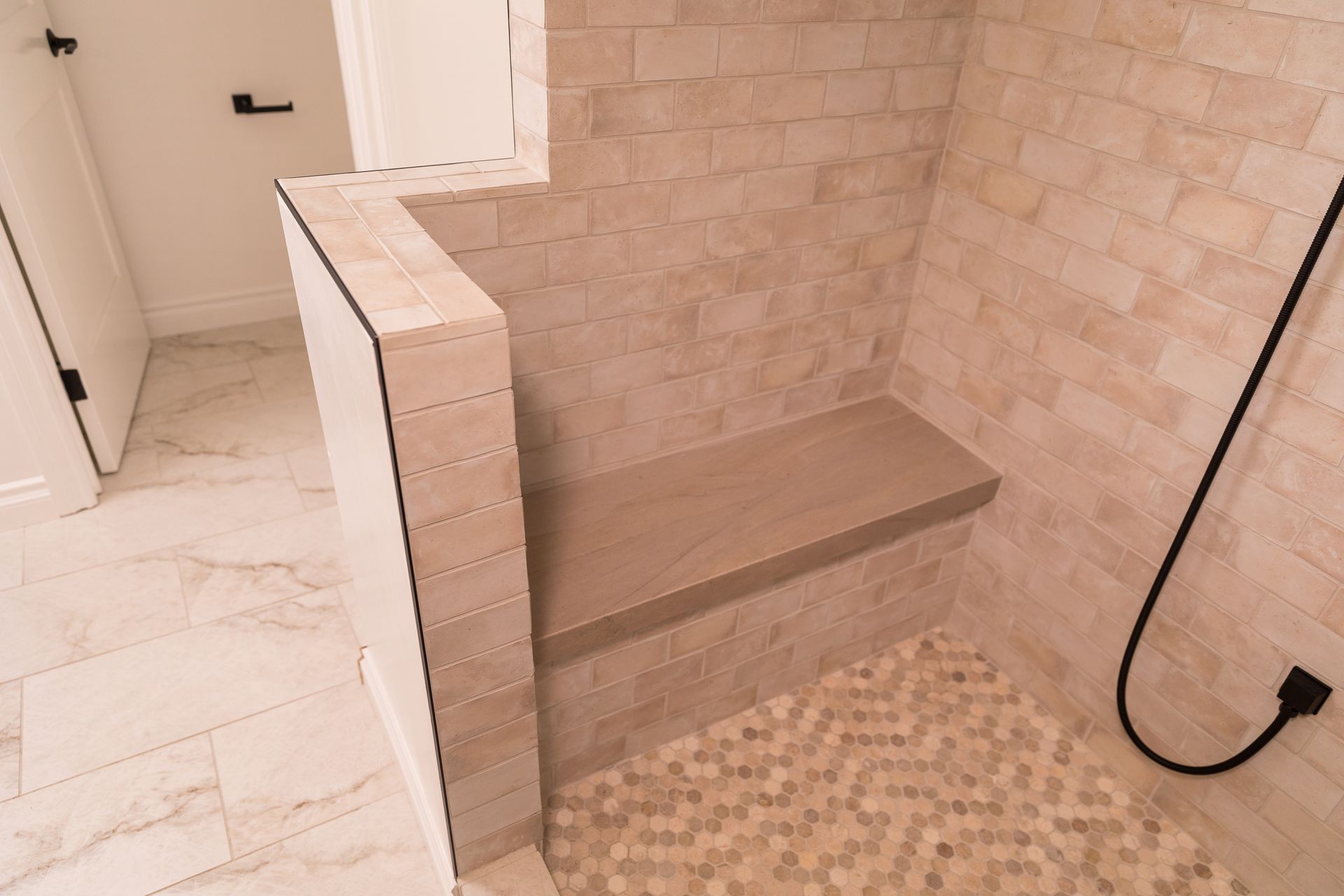 A walk in shower with a bench and a shower head.