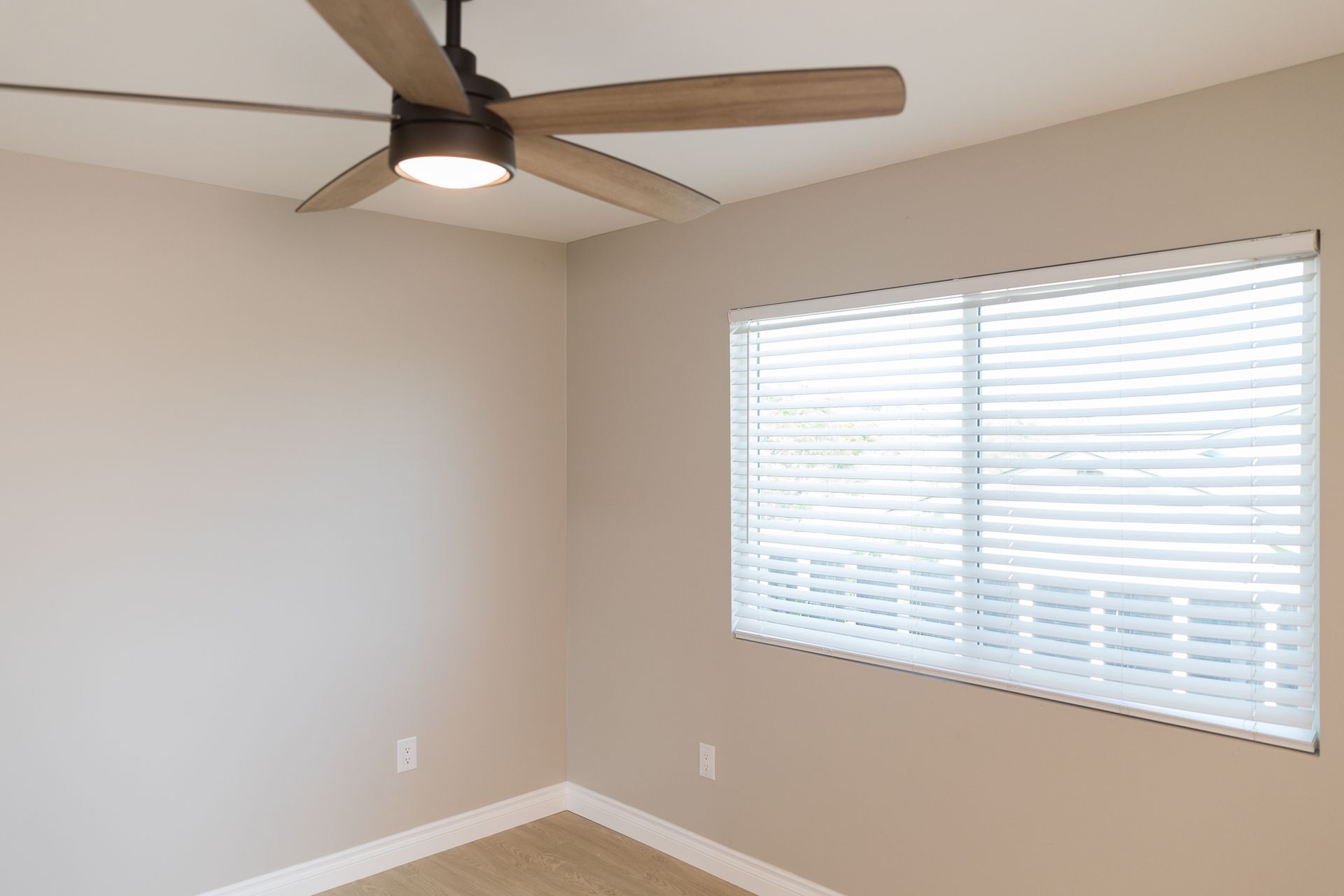 An empty room with a ceiling fan and a window.