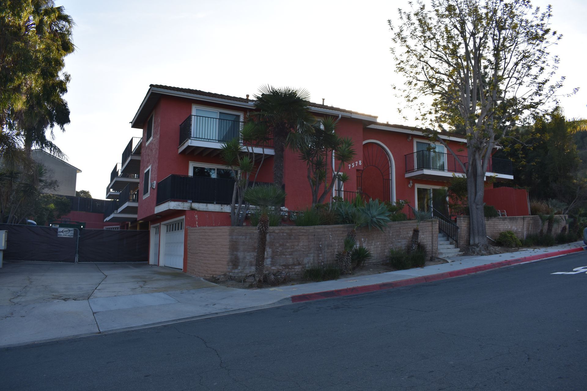 A red apartment building with a handicapped sign on the sidewalk