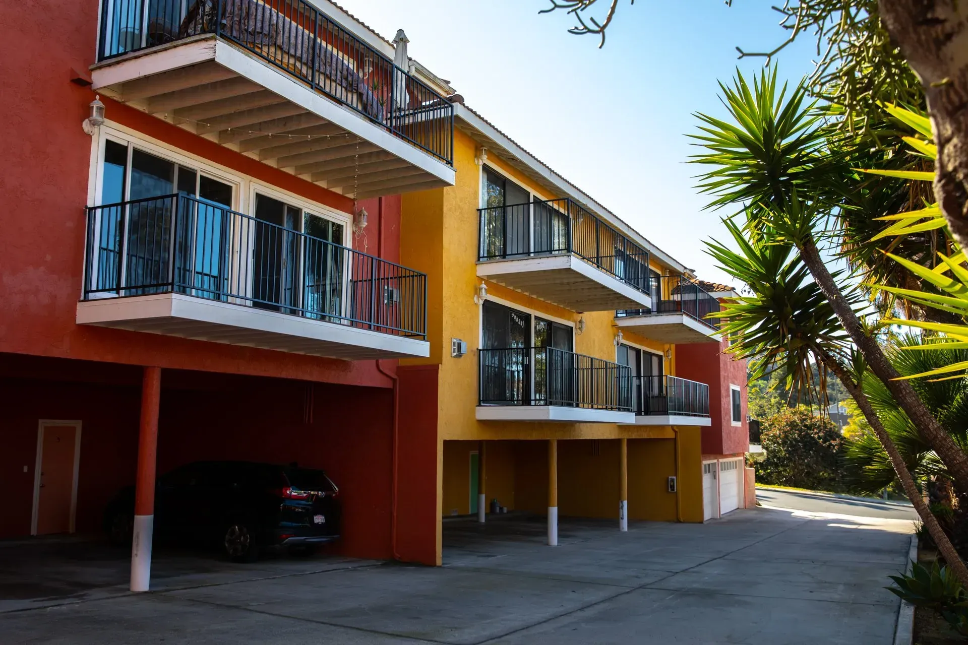 A car is parked in front of a building with balconies