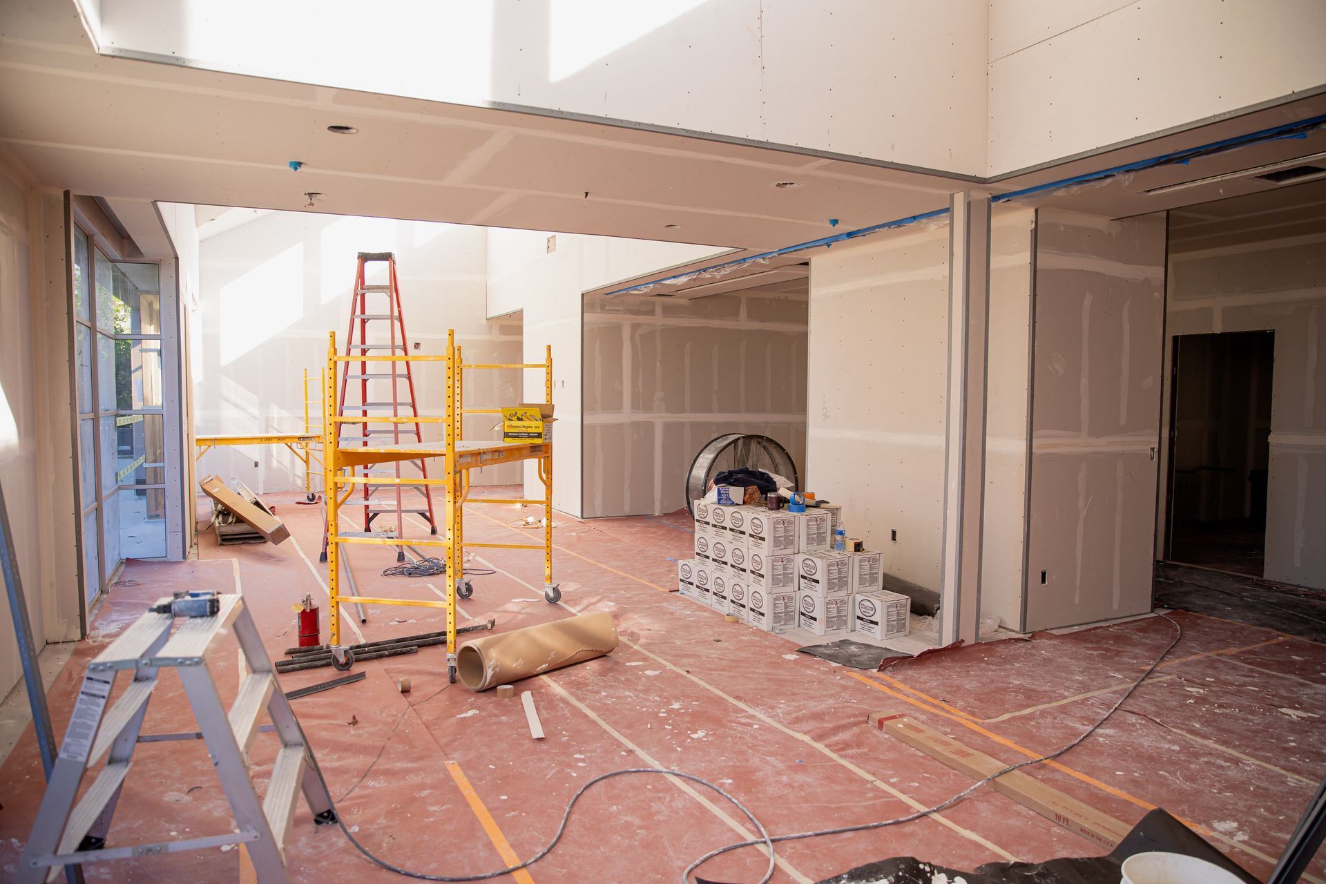 A large room under construction with scaffolding and boxes on the floor.