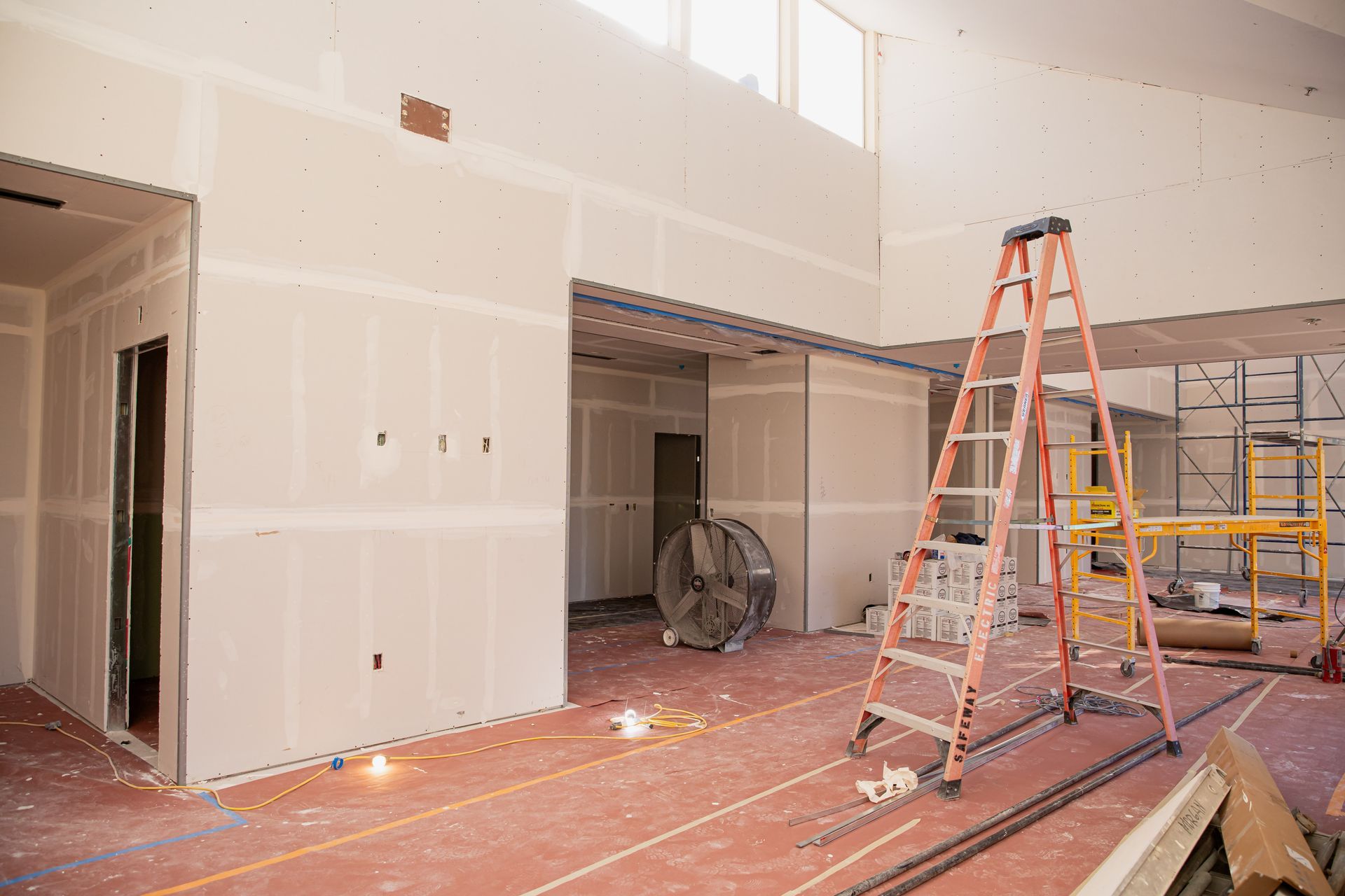 A ladder is sitting in the middle of a room under construction.