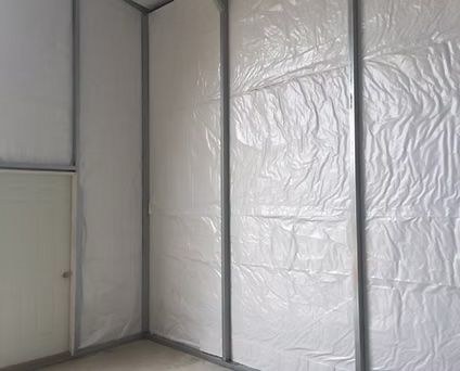 White plastic sheeting covers interior walls within a metal frame.