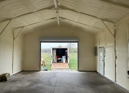 Interior of a building with roll-up door open, showing a trailer; walls and ceiling are insulated.