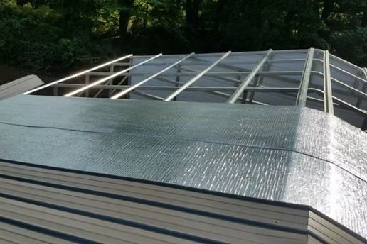 Partially constructed sunroom roof with translucent panels and metal framing.