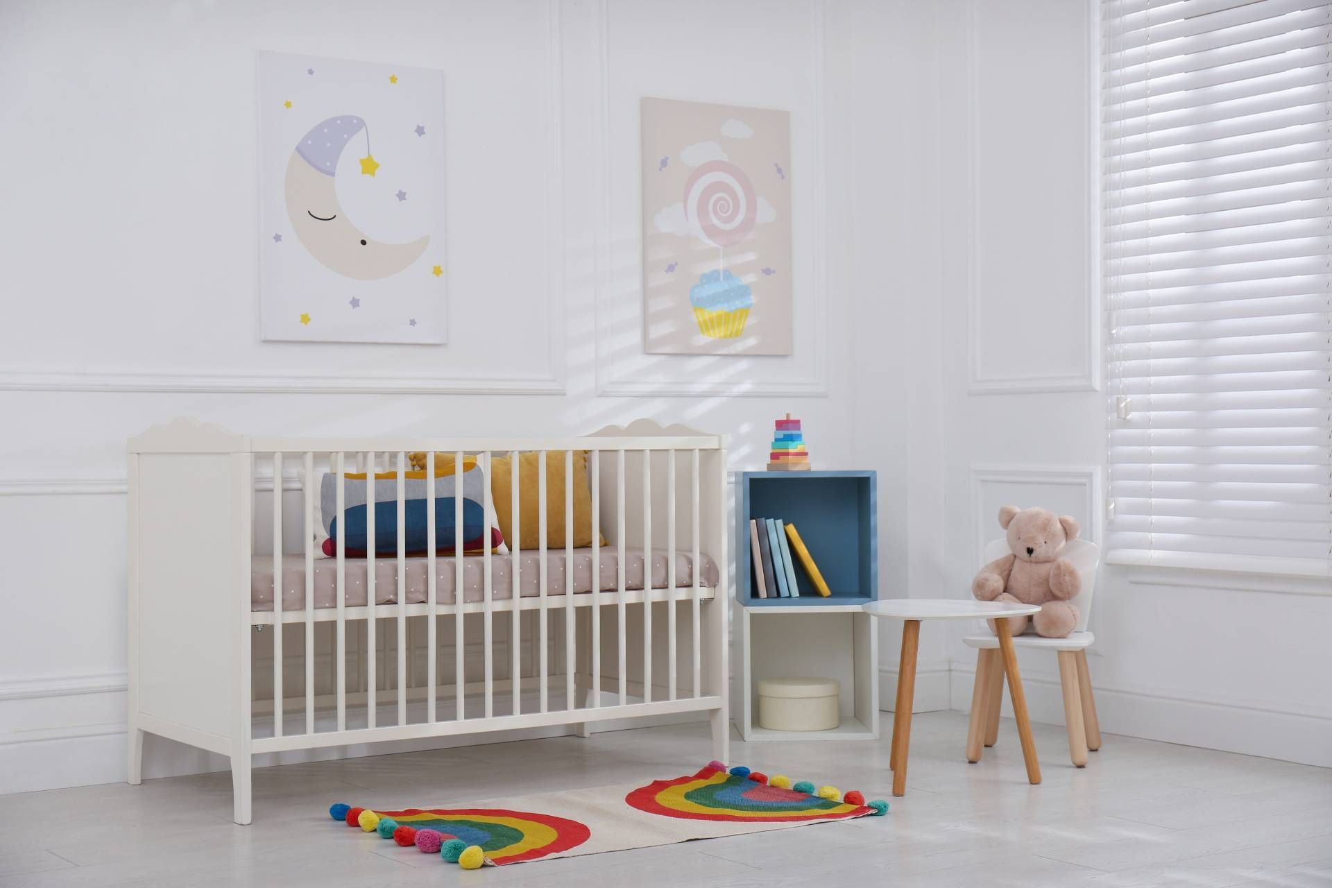 Modern nursery with crib, toys, and white window blinds.