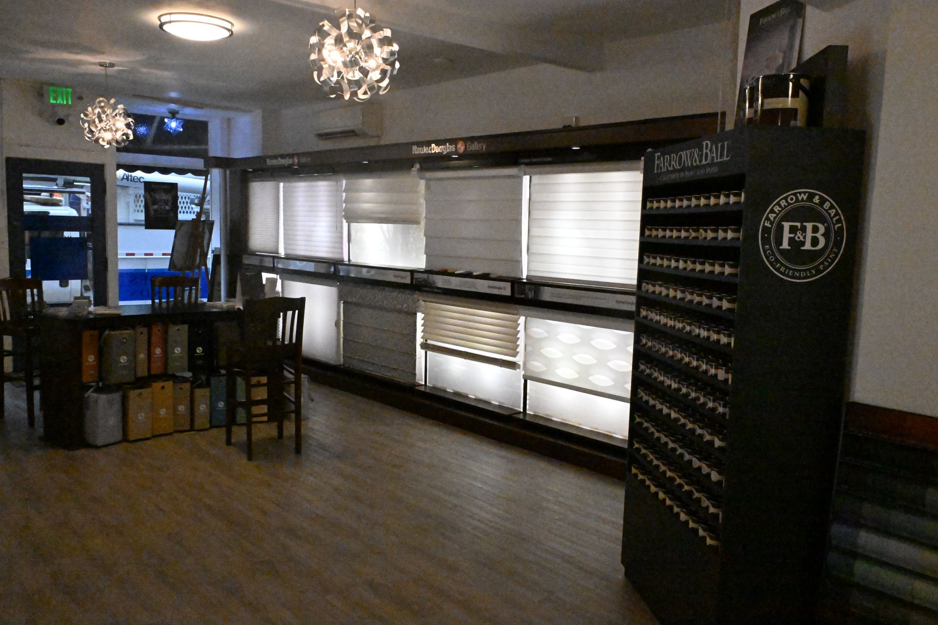 A showroom featuring displays of various window shades and blinds, with a Farrow & Ball paint sample rack on the right.