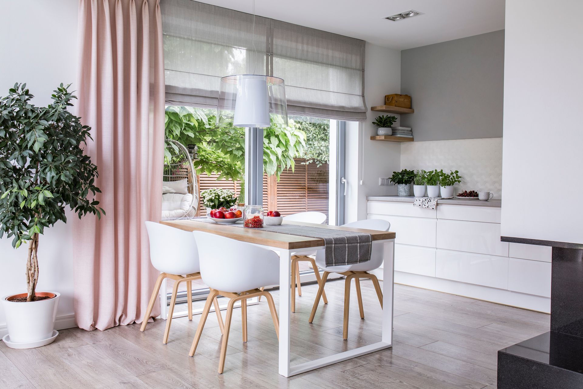 Modern kitchen with pink custom drapery and grey window shades.