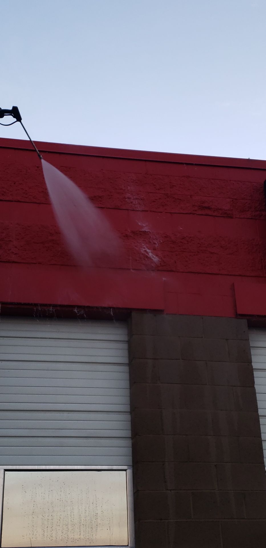 Pressure washing cost-effective solution being applied to restore stained commercial wall surface
