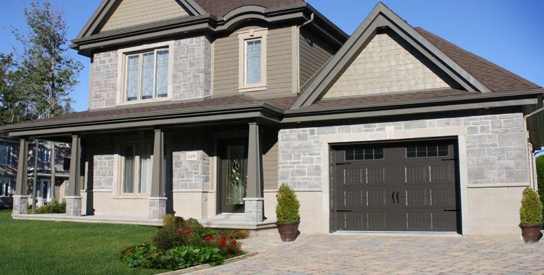 Une grande maison avec un grand garage et un porche.