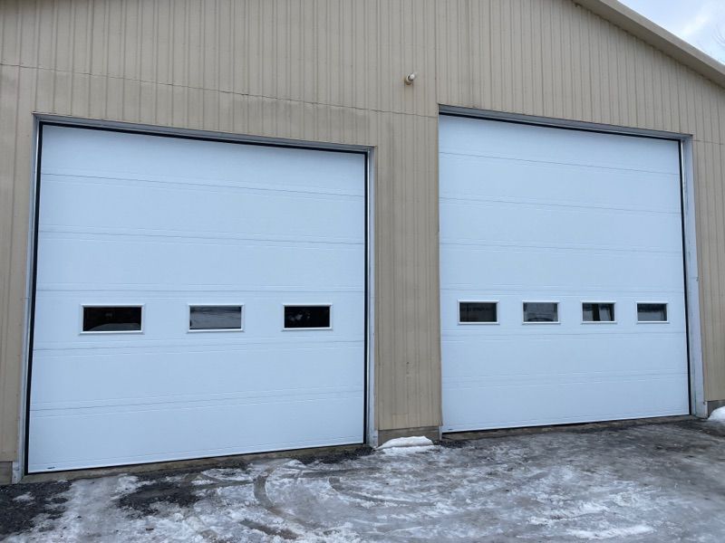 Il y a deux portes de garage blanches sur le côté d'un bâtiment.