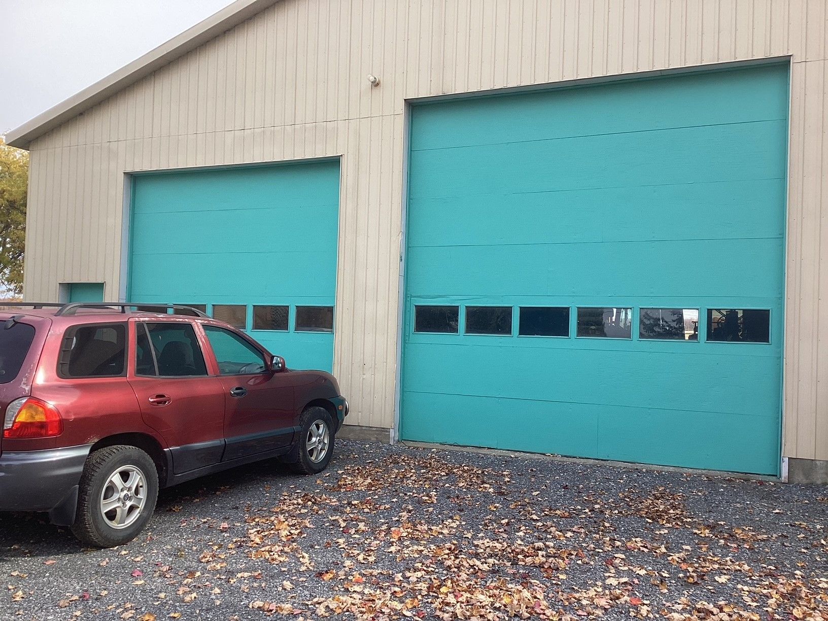 Un SUV rouge est garé devant un garage aux portes bleues.