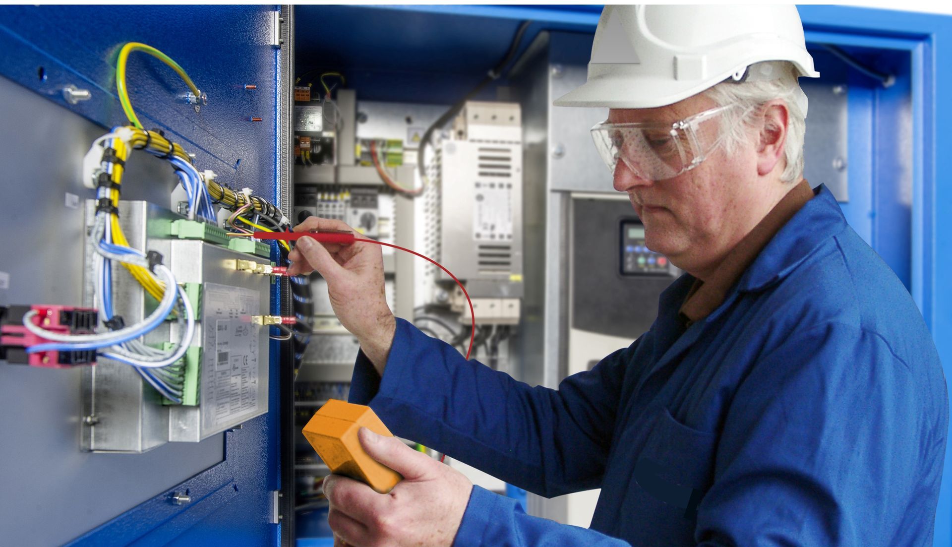 A man wearing a hard hat and safety glasses is working on an electrical box