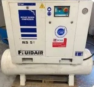 A white air compressor is sitting on top of a wooden pallet.