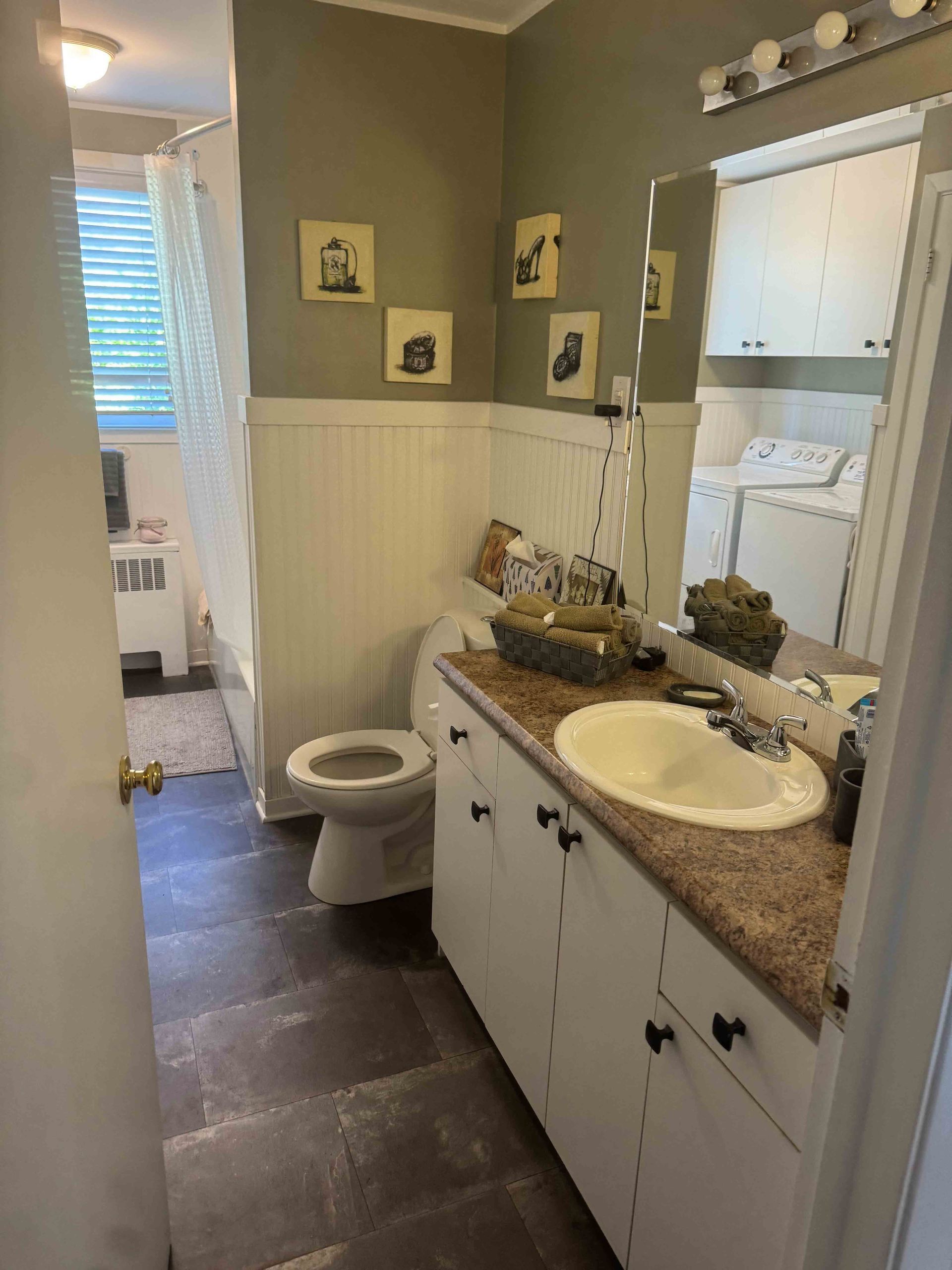 Petite salle de bains avec meuble-lavabo blanc, comptoir en granit, toilettes, miroir et murs gris.
