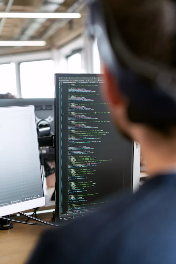 Person viewing a code editor on a monitor in a bright office workspace