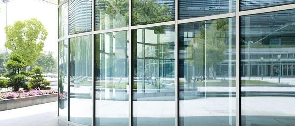 Un gran edificio de cristal con muchas ventanas y árboles al fondo.
