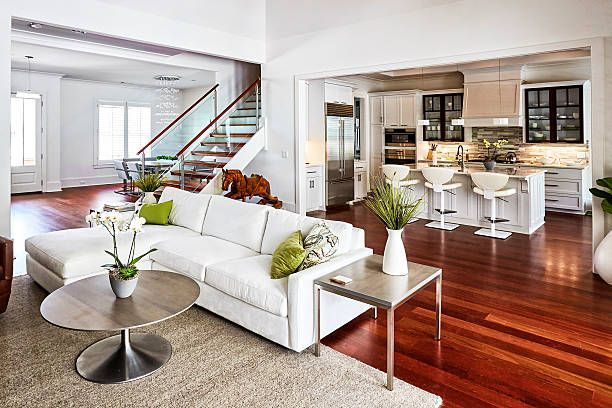 A living room with a white couch , coffee table , and stairs leading to the kitchen.