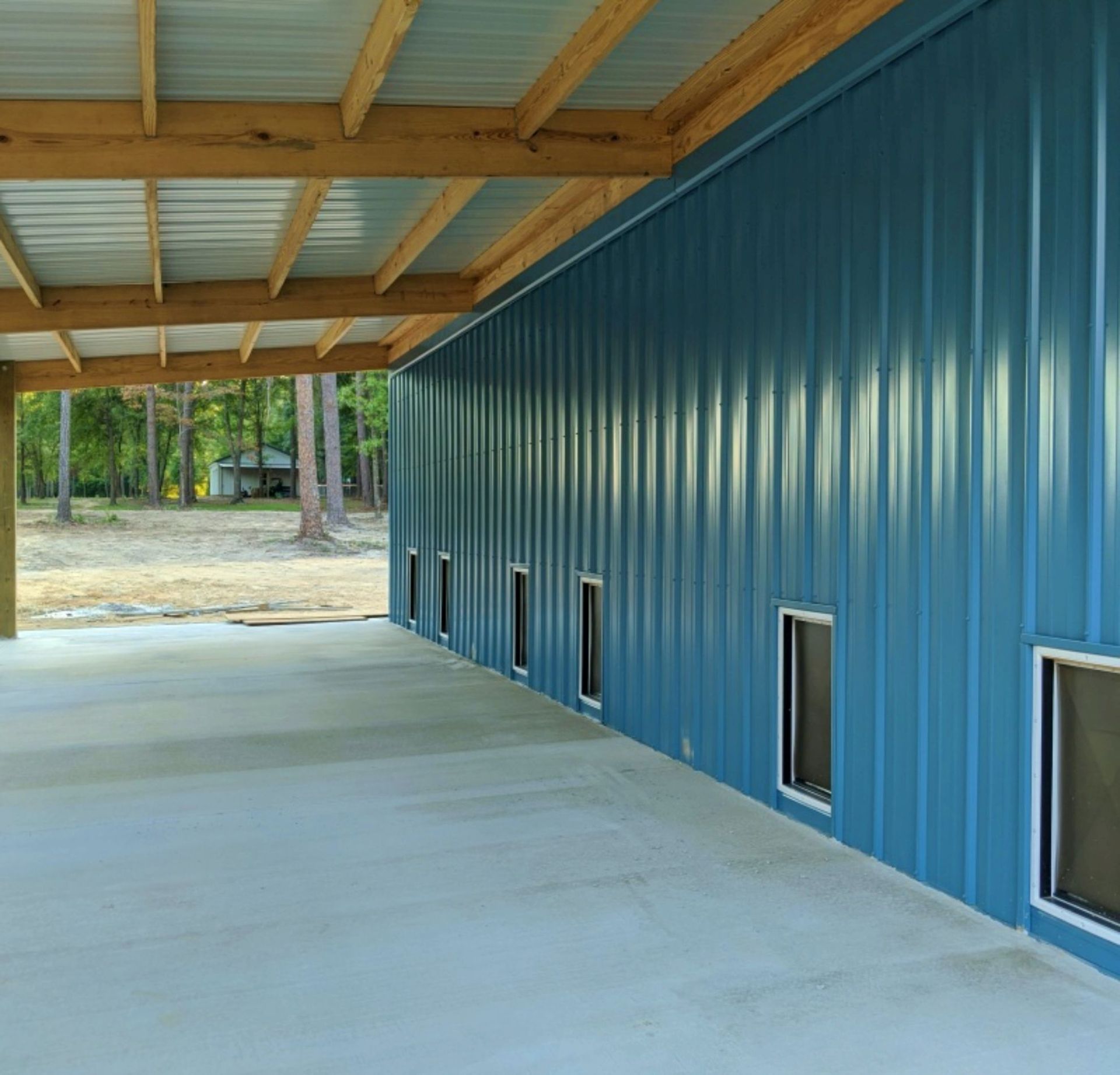 Covered concrete walkway beside a blue metal building with small windows