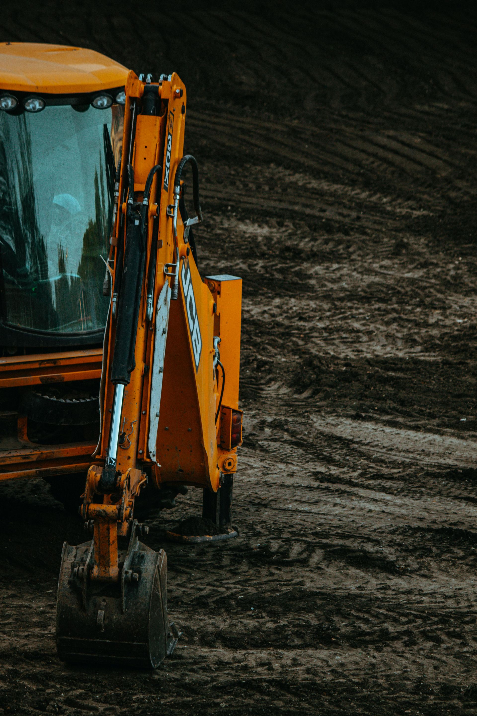 Orange excavator digging in a dark dirt field