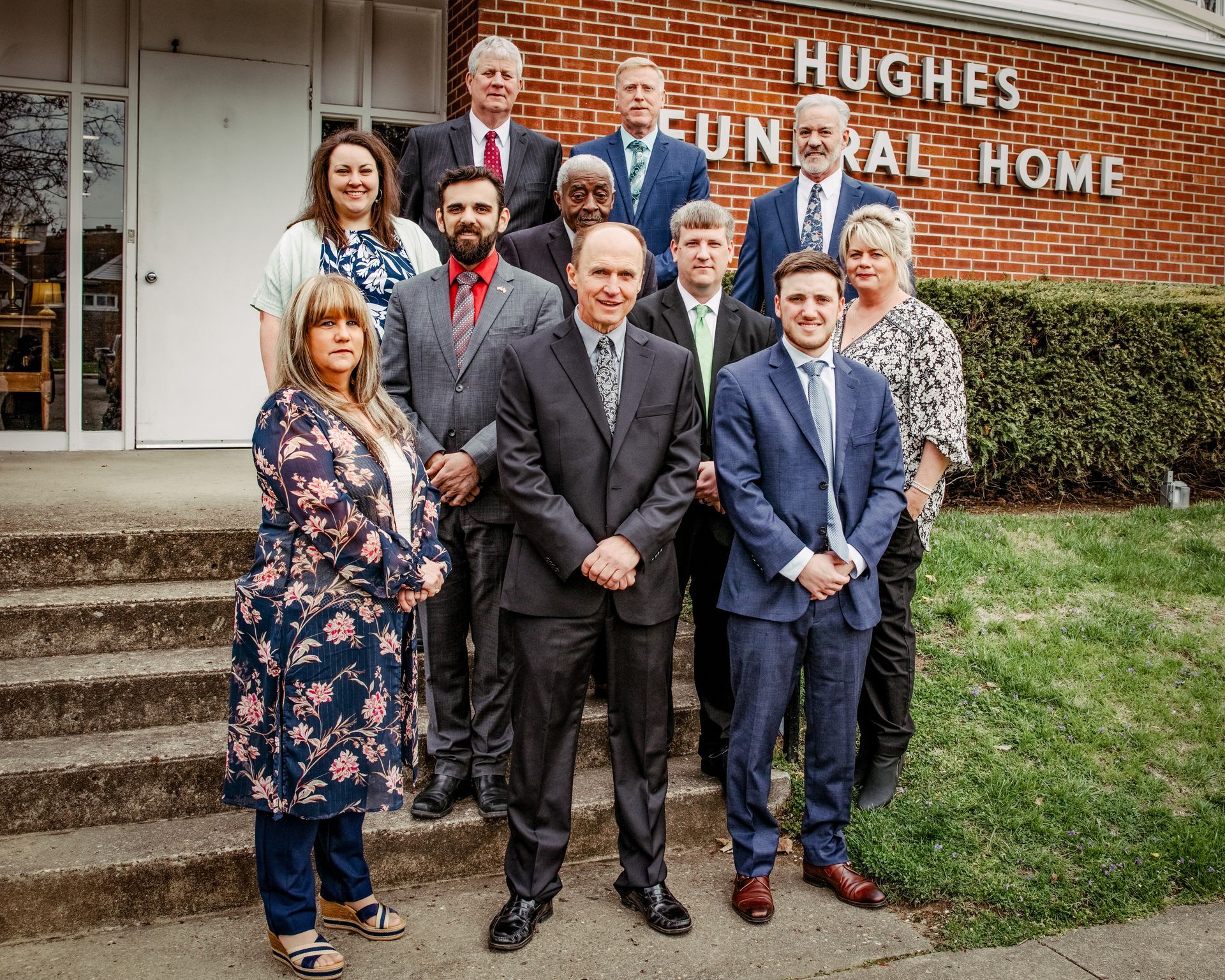 A group of people are posing for a picture in front of a funeral home.