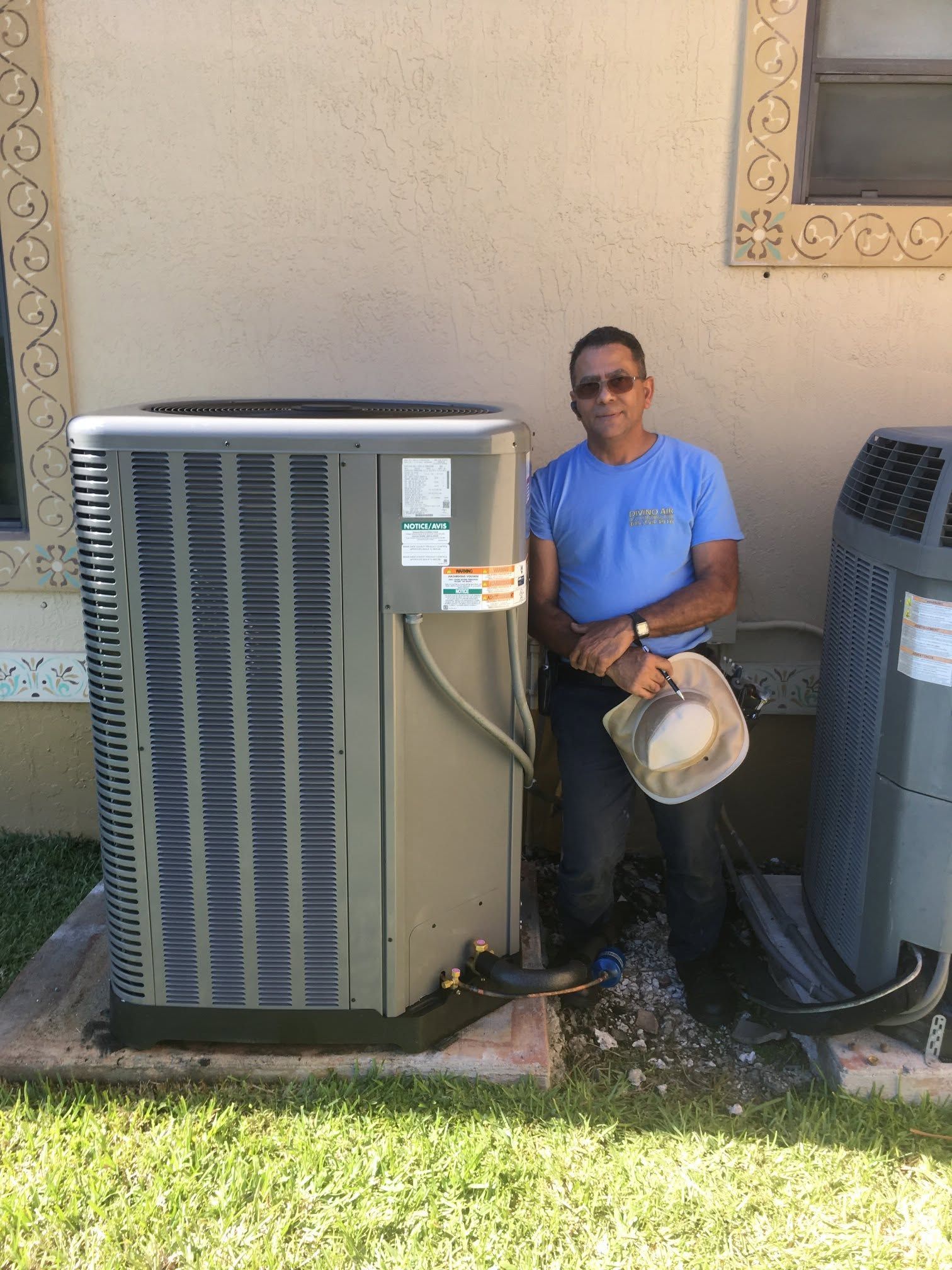 Technician inspecting electrical equipment outdoors beside a beige wall, with wires and tools visible.