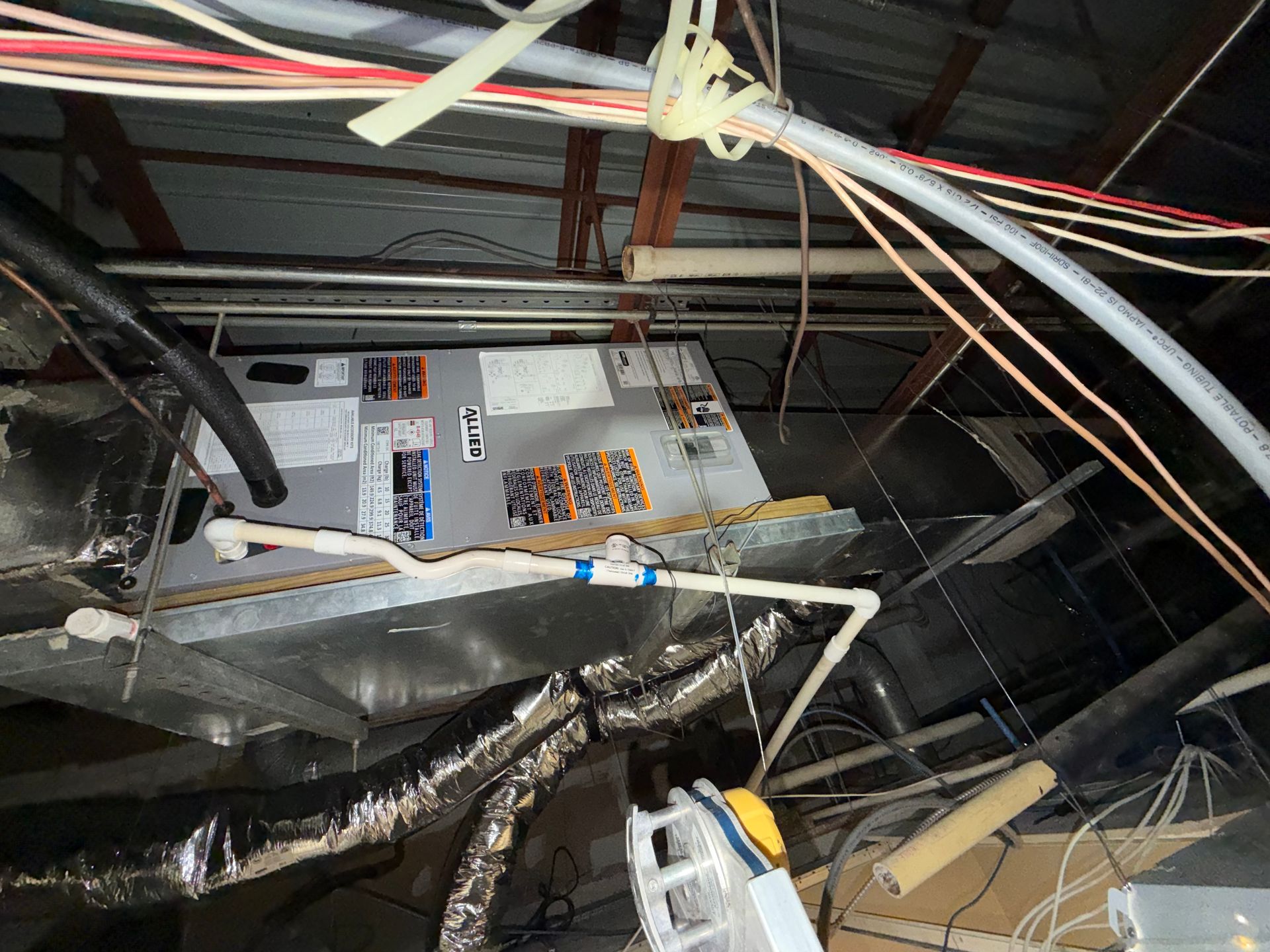 Collapsed ceiling with exposed wires and damaged debris in a cluttered indoor space