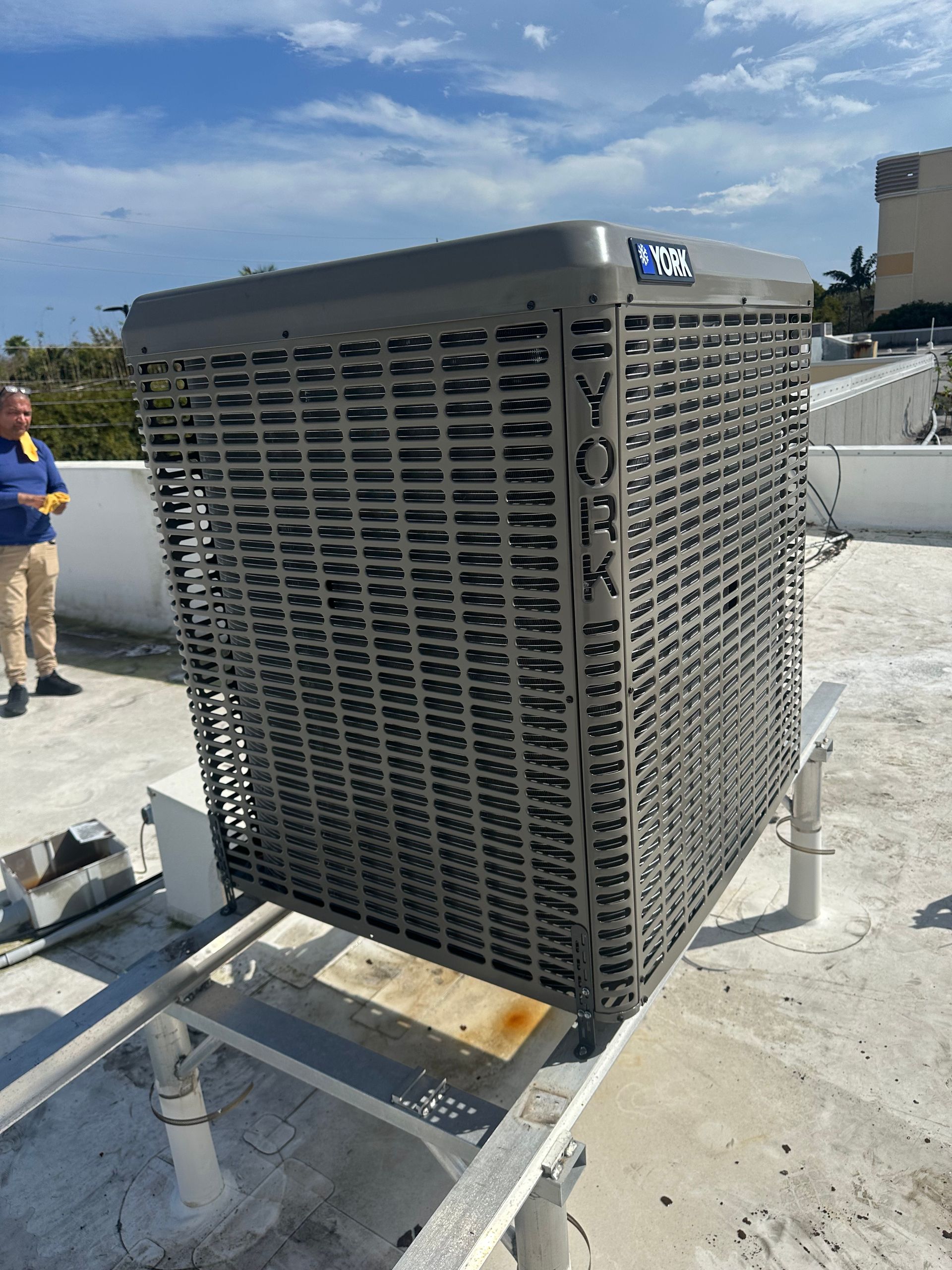 Large rooftop HVAC unit with metal grilles on a concrete surface under a blue sky