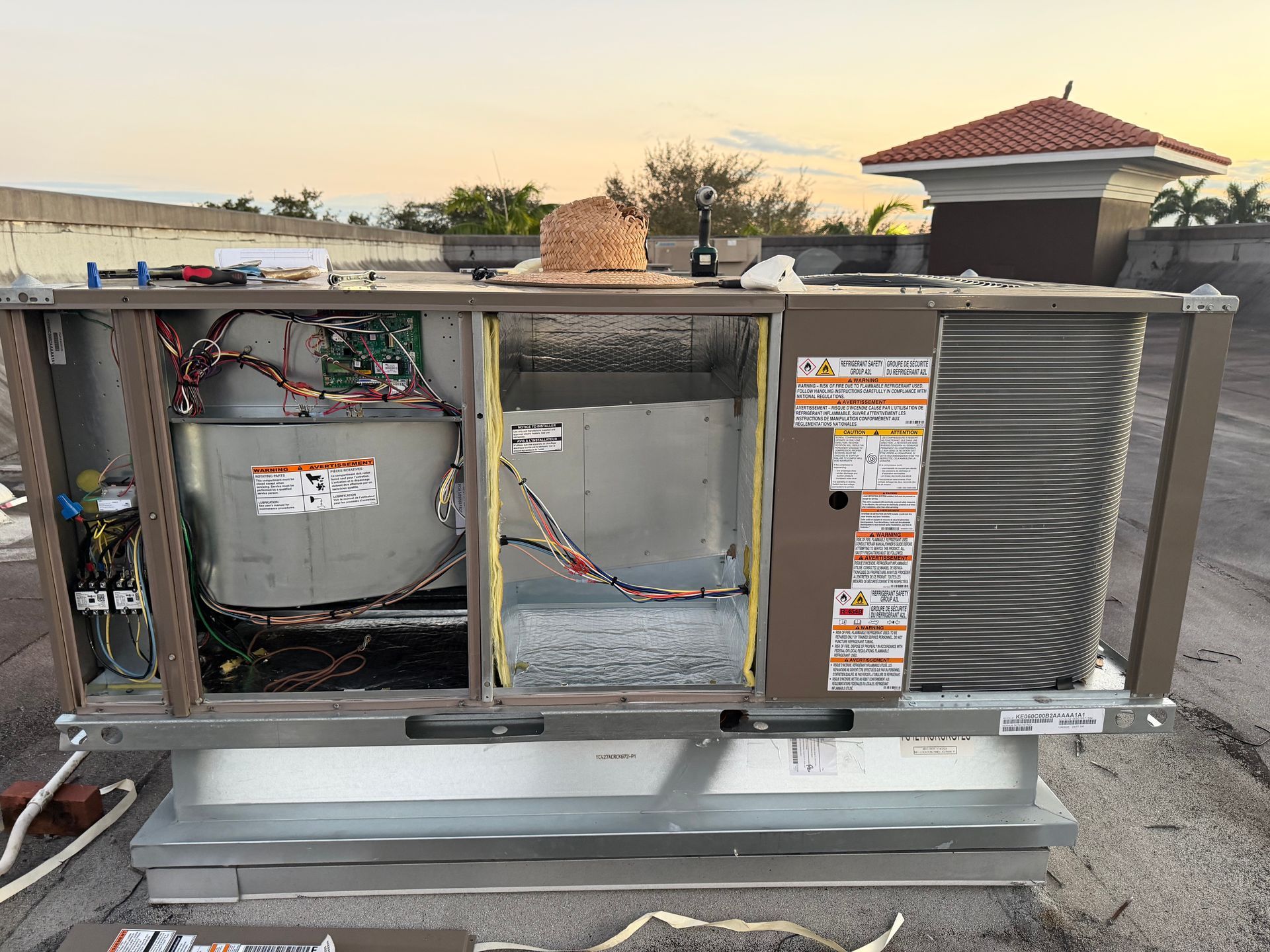 Large HVAC unit with exposed wiring and ductwork on a rooftop, showing internal components and labels
