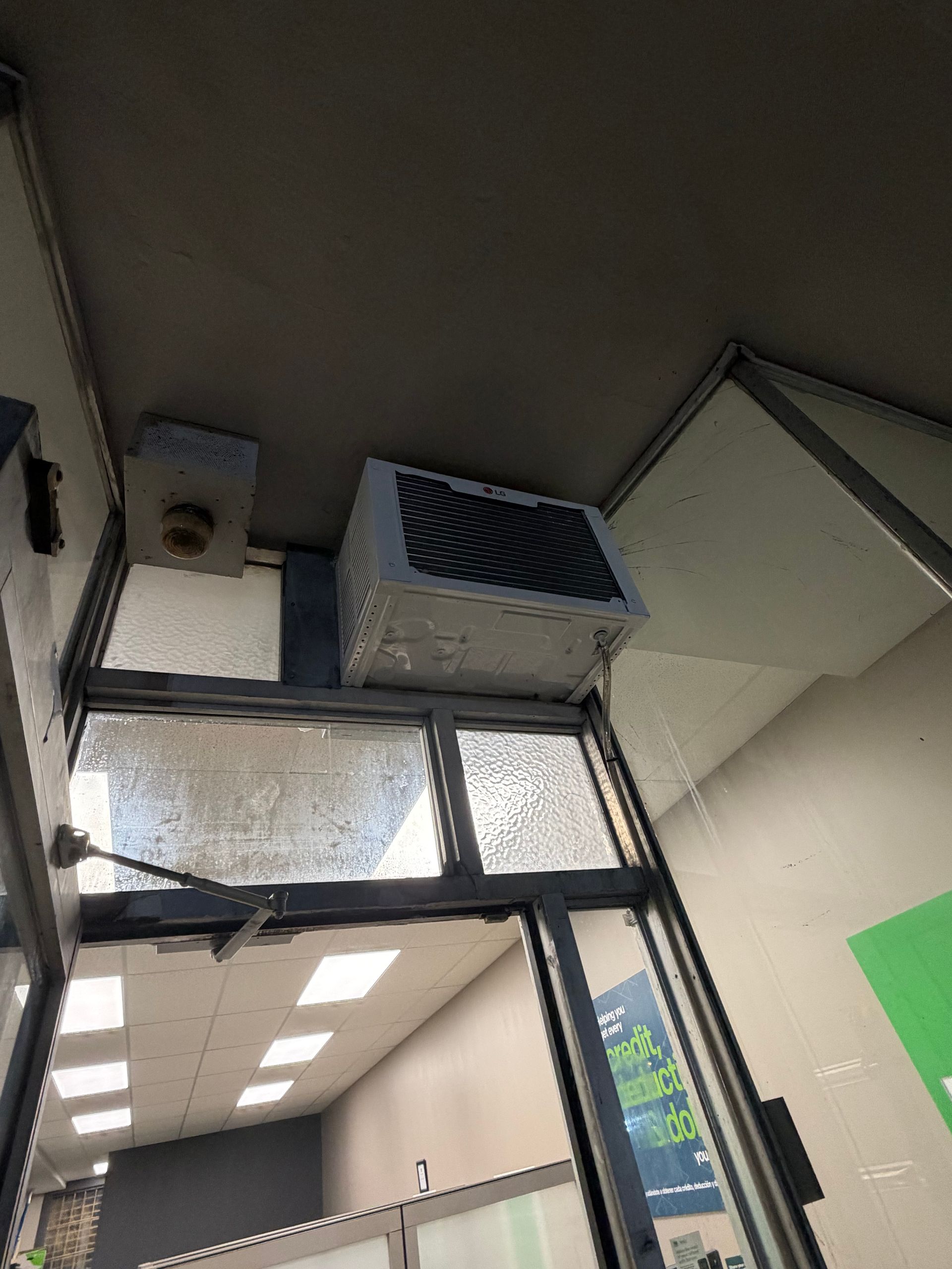 Indoor ceiling with ventilation units above a doorway and fluorescent lights in a hallway