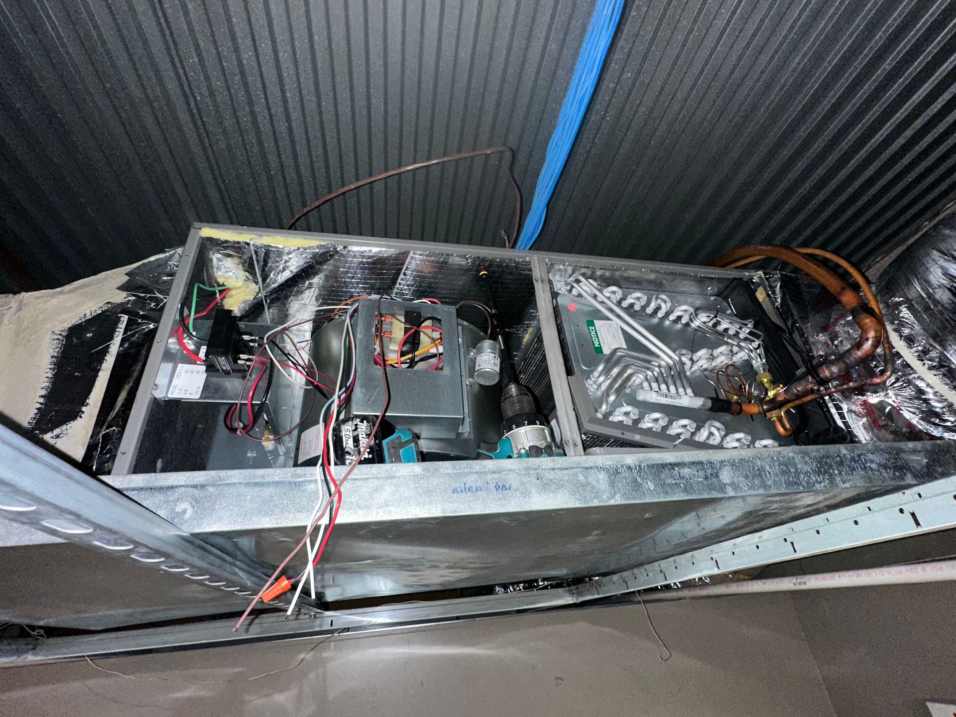 Damaged metal enclosure with exposed wiring and batteries inside a narrow space