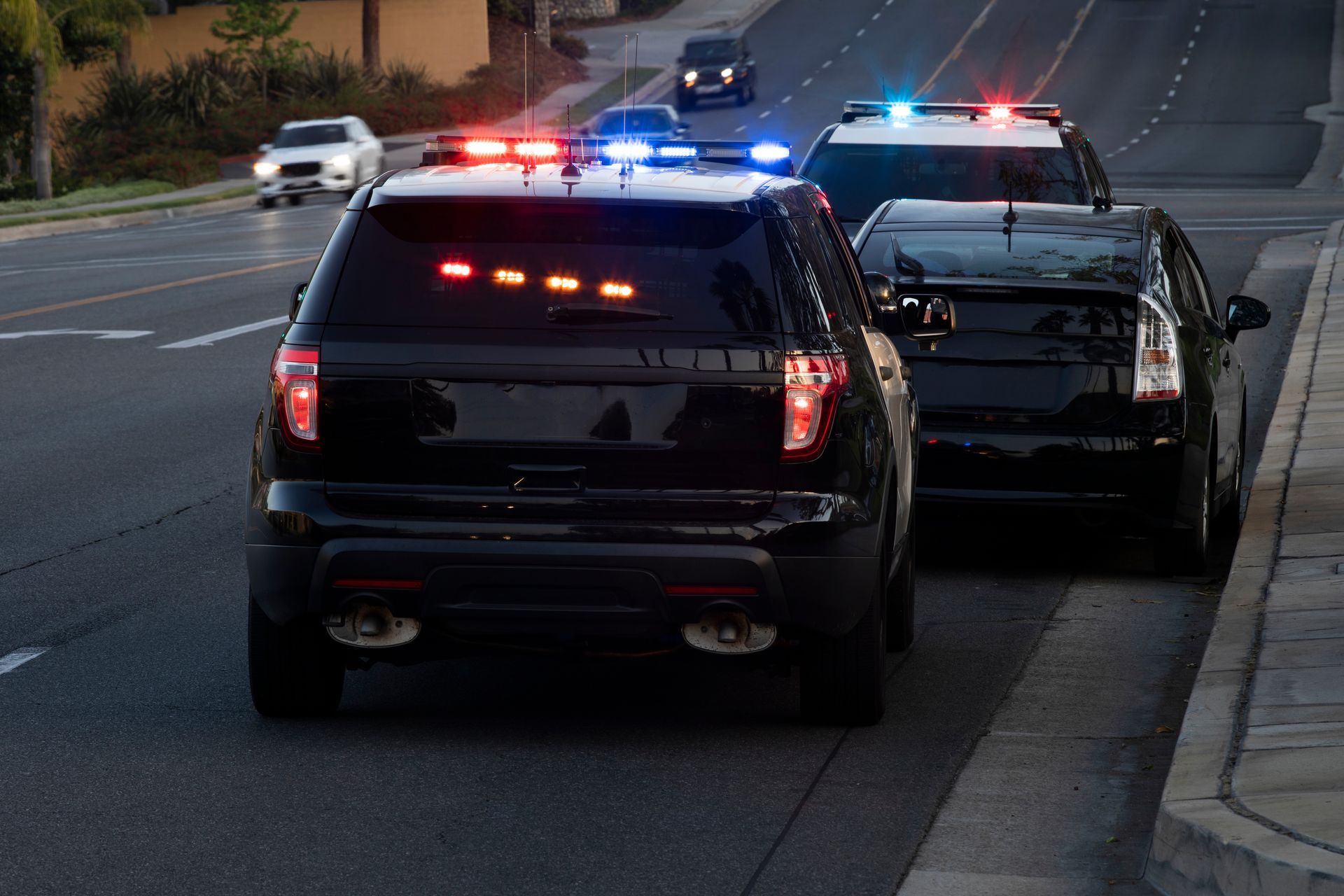 Police SUV with flashing lights conducting a traffic stop on a car pulled to the roadside