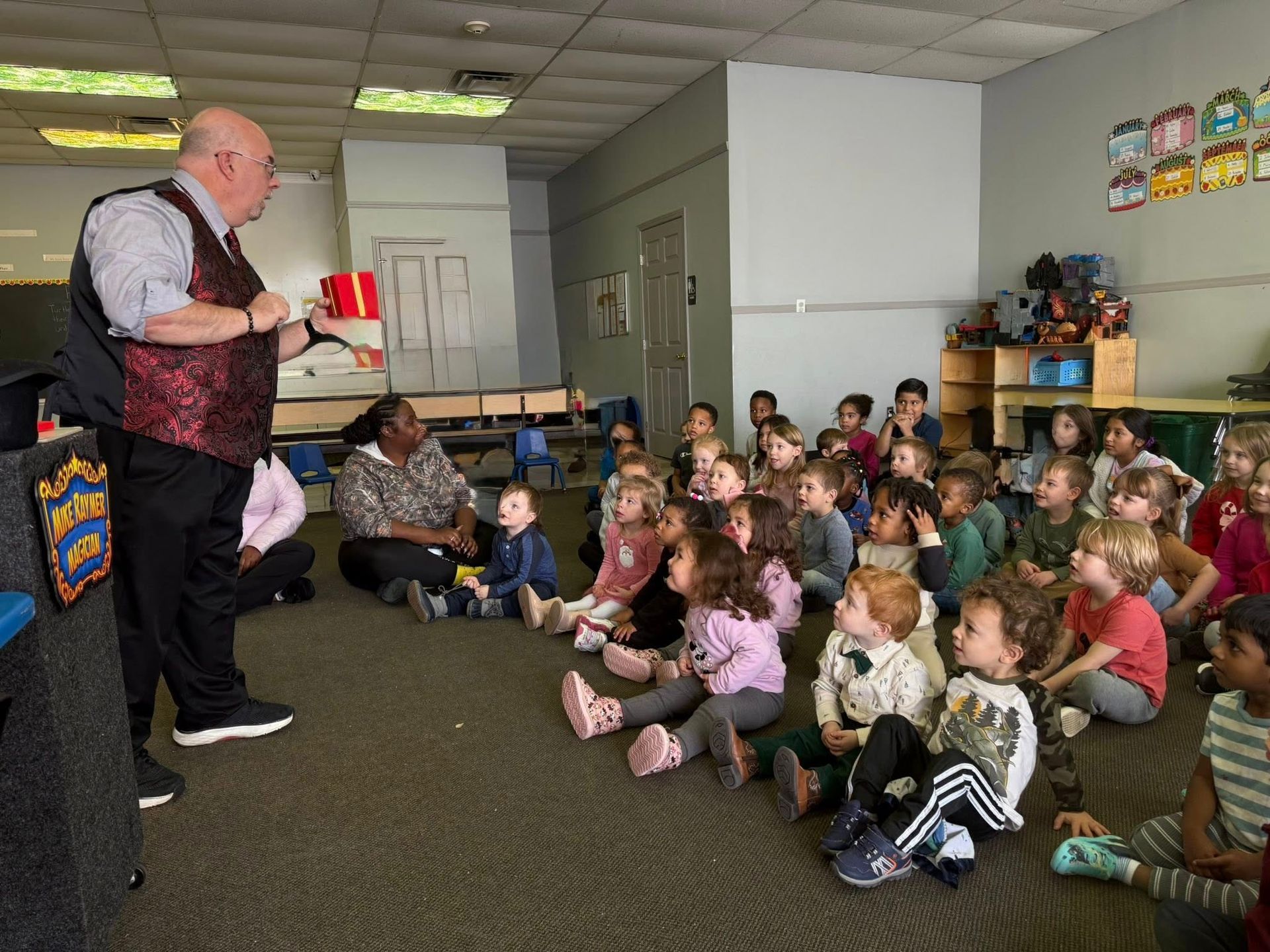 Speaker reading to seated children in a classroom or library.