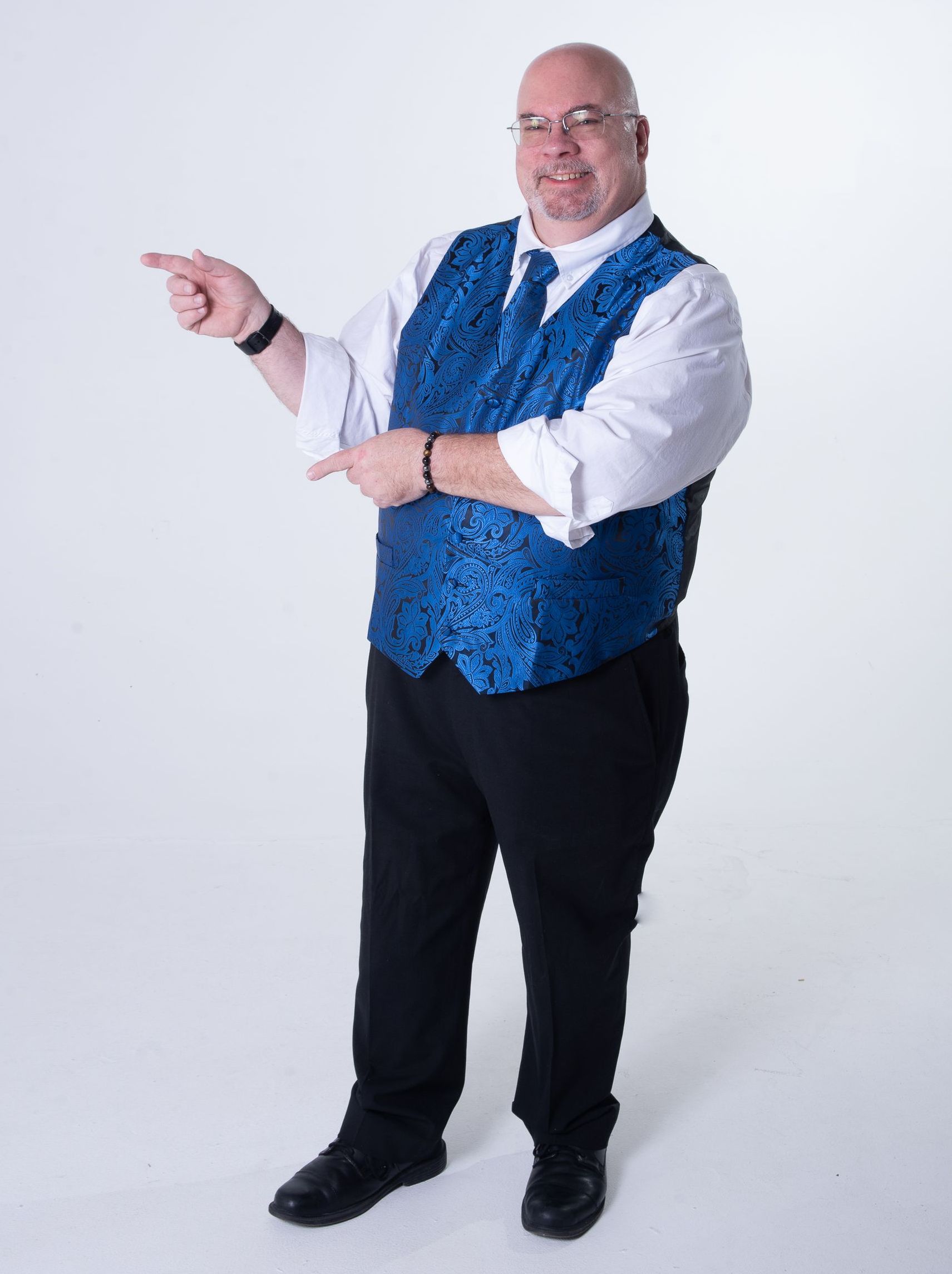 Man in blue sequined vest points left and right, smiling.