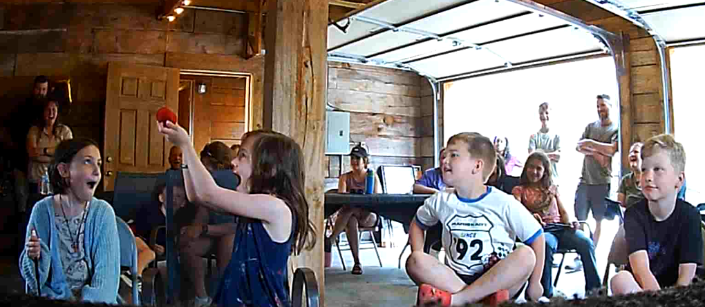 Children sitting and gesturing in a bright rustic indoor room