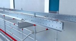 Estrutura metálica com trilhos e suportes com tampas vermelhas em um interior industrial.