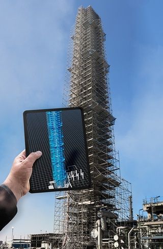 Mão segurando um tablet mostrando um arranha-céu envolto em andaimes contra um céu azul.