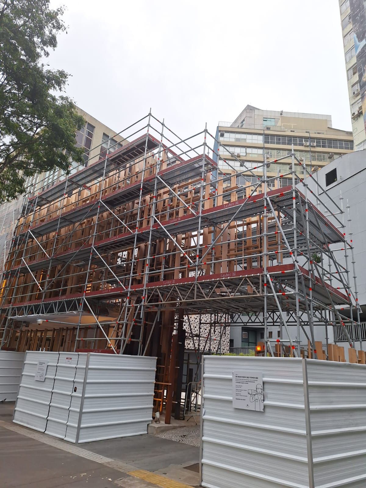Andaimes em volta de um prédio em construção, com painéis de barricada brancos na frente.