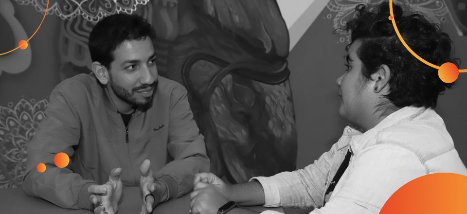 Dois homens estão apertando as mãos enquanto estão sentados à mesa.