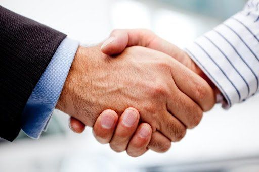Dois homens estão apertando as mãos em um close de suas mãos.