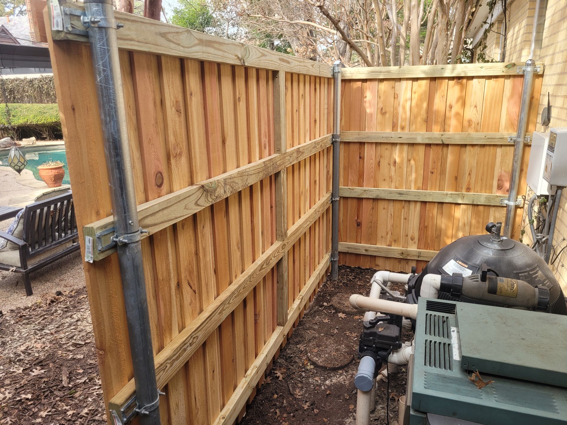 Wooden fence panels and gate beside a large black water tank in an outdoor yard area
